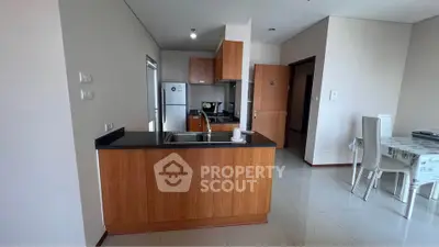 Modern kitchen with sleek wooden cabinets and dining area in open layout apartment.