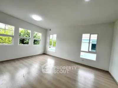 Spacious empty room with large windows and wooden flooring, perfect for customization.