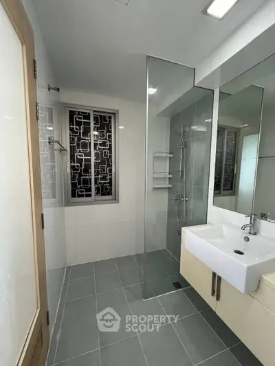 Modern bathroom with glass shower and stylish sink in contemporary apartment.