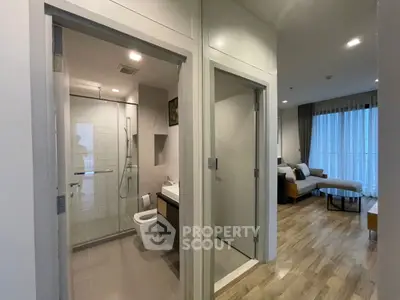 Modern apartment interior with bathroom and living room, featuring sleek design and natural lighting.
