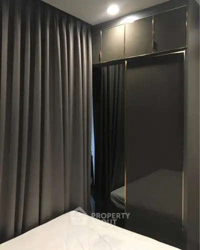 Modern bedroom with sleek mirrored wardrobe and elegant curtains