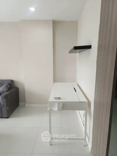 Modern minimalist living room with sleek white desk and cozy gray sofa, perfect for urban living.