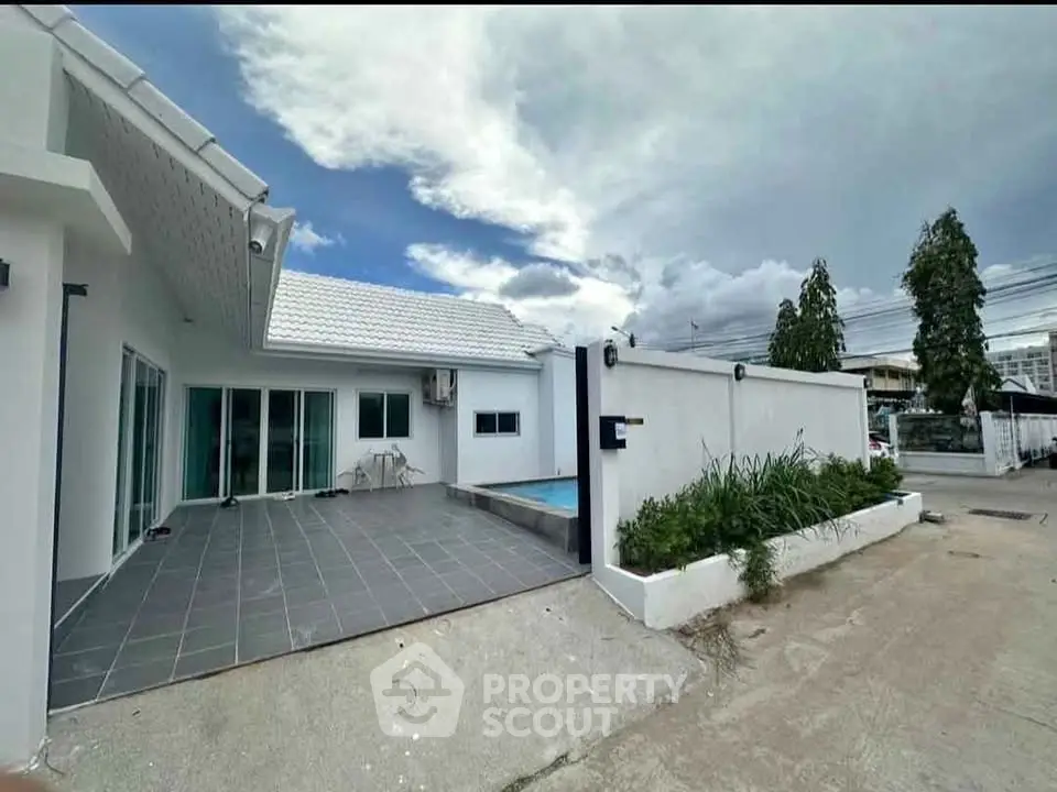 Modern white house with spacious patio and small pool, perfect for outdoor relaxation.