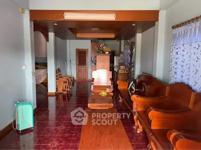 Spacious living room with wooden furniture and tiled flooring, perfect for family gatherings.