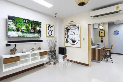 Modern living room with stylish decor and wall-mounted TV, open layout to kitchen.