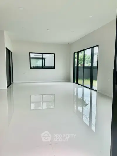 Spacious modern living room with large windows and glossy white flooring