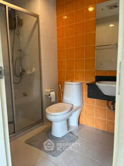 Modern bathroom with glass shower and orange accent tiles