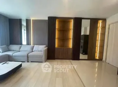 Modern living room with sleek design and built-in wooden shelves, featuring a cozy gray sofa and stylish coffee table.