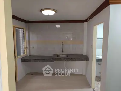 Compact kitchen area with granite countertop and sink, adjacent to a bathroom.