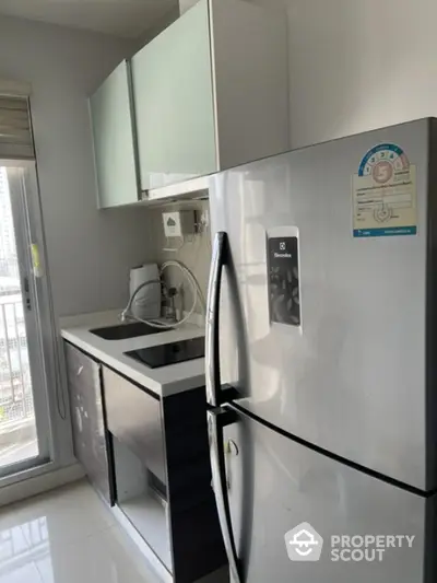 Modern kitchen with stainless steel fridge and sleek cabinetry in a bright apartment