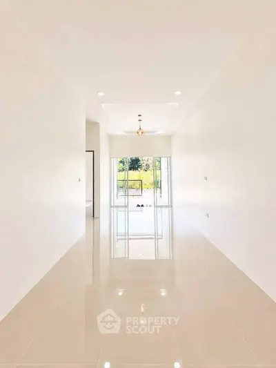 Spacious modern living room with glossy tiled floors and large windows offering natural light.
