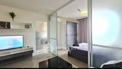 Modern apartment with sleek living room and cozy bedroom separated by glass partition.