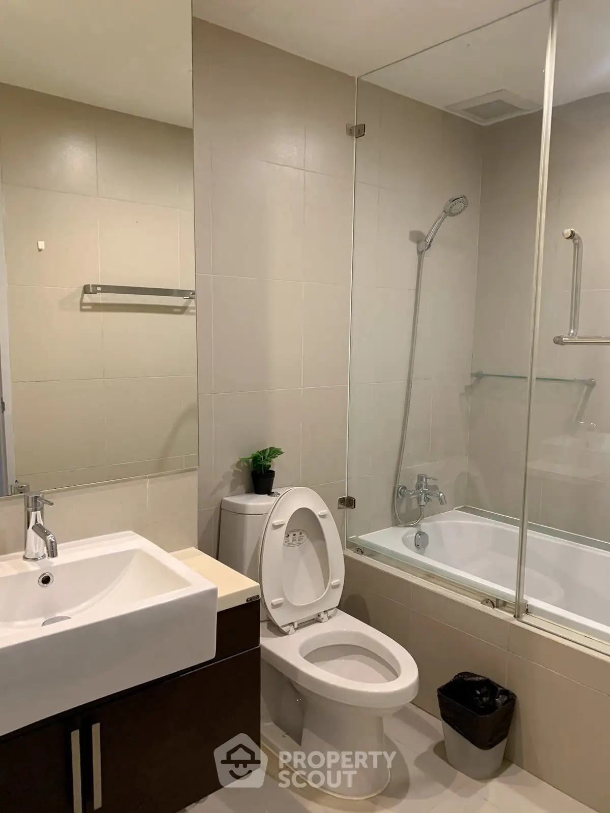 Modern bathroom with glass-enclosed bathtub and sleek fixtures in a contemporary apartment.
