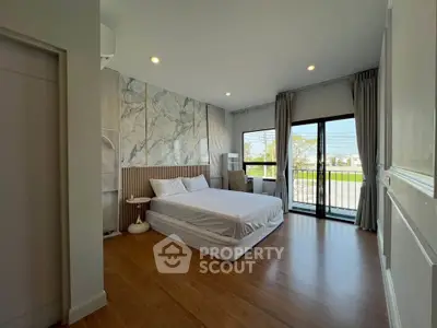 Spacious bedroom with large windows and modern decor, offering a serene view.