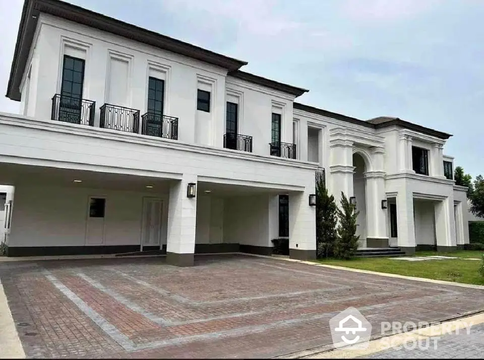 Luxurious modern white villa with spacious driveway and elegant architectural design.