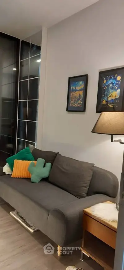 Cozy living room with modern gray sofa, colorful cushions, and stylish wall art.
