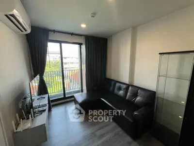 Modern living room with sleek black sofa and balcony view, perfect for urban living.