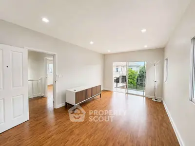 Spacious living room with wooden flooring and balcony access in modern home