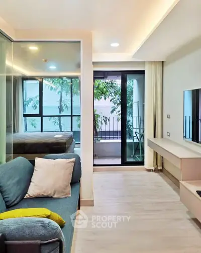 Modern living room with glass partition and balcony view, featuring sleek furniture and natural light.