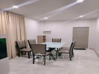 Modern dining area with glass table and six chairs in a well-lit room.