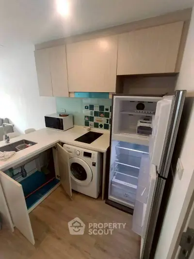 Modern kitchen with integrated appliances including fridge and washing machine, sleek cabinetry, and open layout.