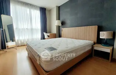 Spacious modern bedroom with large window and stylish furnishings.