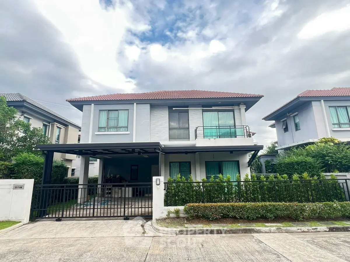 Modern two-story house with gated driveway and lush greenery in a serene neighborhood.
