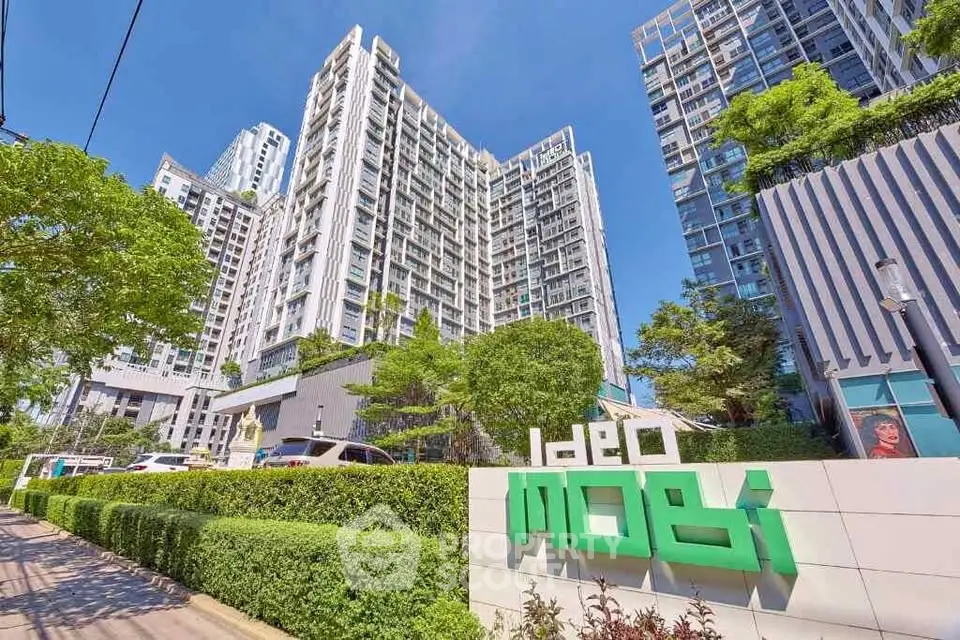 Modern high-rise condominium with lush greenery and clear blue sky