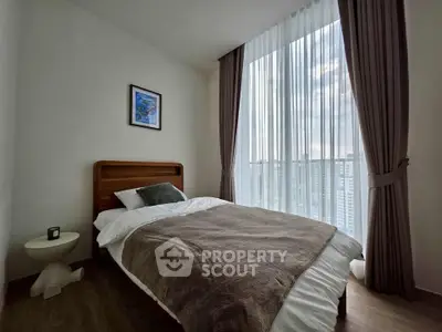 Cozy bedroom with large window and elegant curtains in modern apartment.