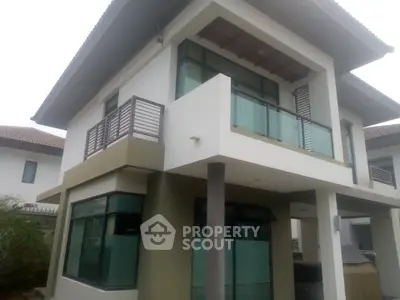 Modern two-story house with large windows and balcony, showcasing contemporary architecture.