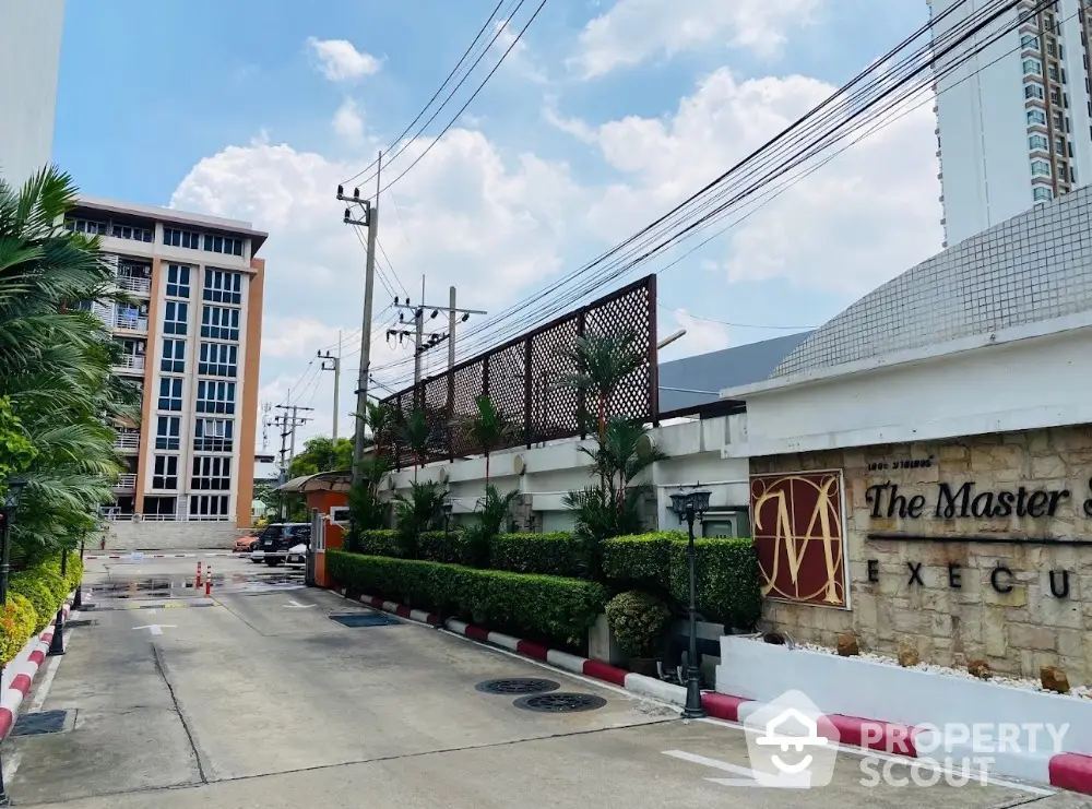 Modern condominium entrance with lush greenery and clear blue sky