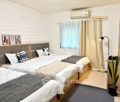 Spacious bedroom with three beds, modern decor, and natural light.