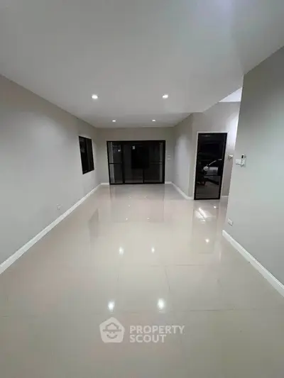 Spacious empty living room with glossy tiled floors and large windows.