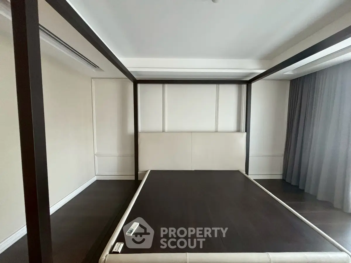 Spacious bedroom with elegant four-poster bed frame and large windows