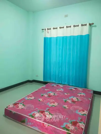 Cozy bedroom with vibrant floral mattress and blue curtains, perfect for a restful retreat.