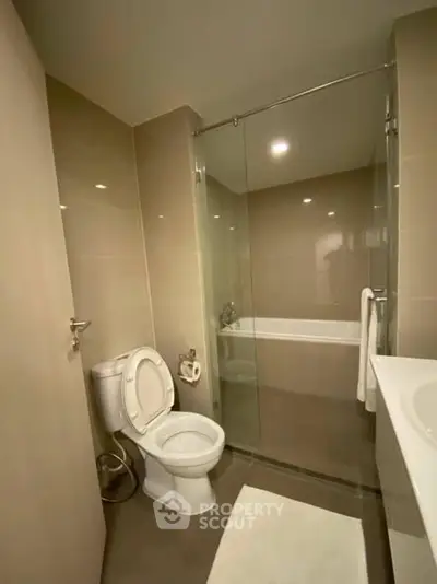 Modern bathroom with glass shower and bathtub in sleek apartment