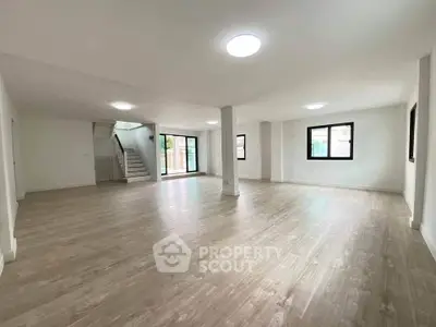 Spacious open-plan living area with wooden flooring and large windows