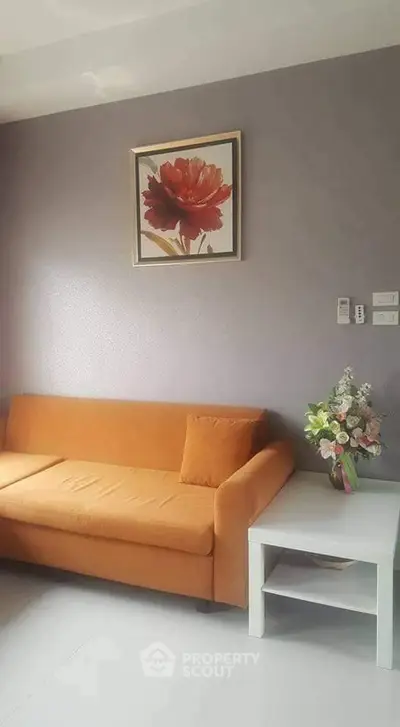 Cozy living room with orange sofa and floral artwork, perfect for relaxation.