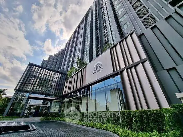 Modern high-rise building with sleek architecture and lush landscaping.