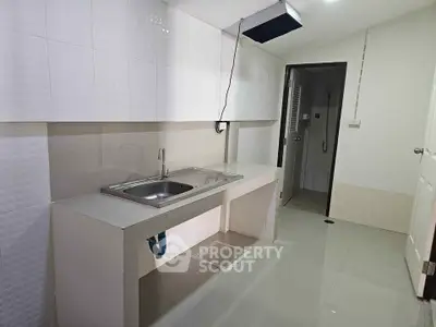 Modern minimalist kitchen with sleek white tiles and stainless steel sink