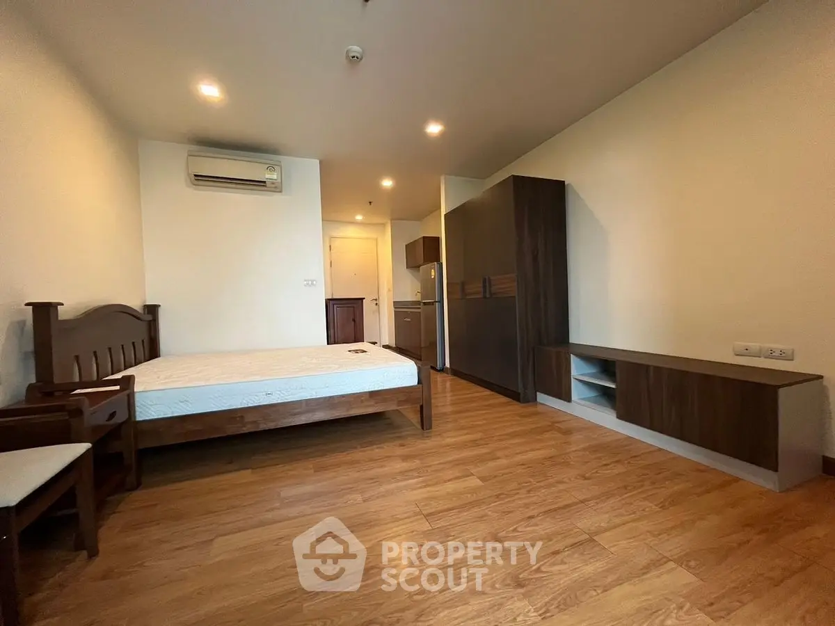 Spacious bedroom with wooden flooring and modern furniture