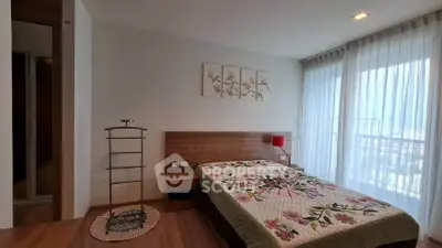 Spacious bedroom with floral decor and large window offering natural light.