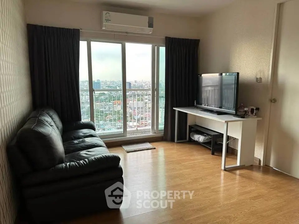Spacious living room with city view, featuring a black leather sofa and a flat-screen TV, perfect for relaxation.
