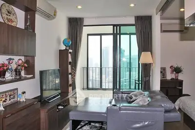 Modern living room with city view, featuring sleek furniture and floor-to-ceiling windows.