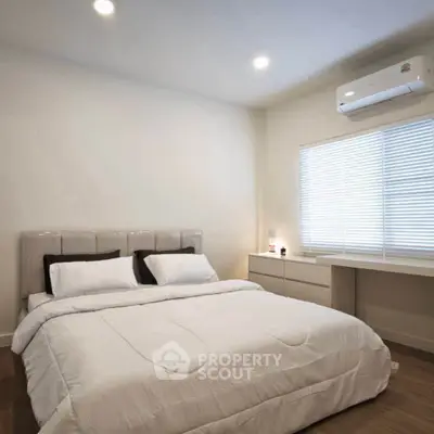 Modern bedroom with cozy bed and air conditioning in a bright setting.