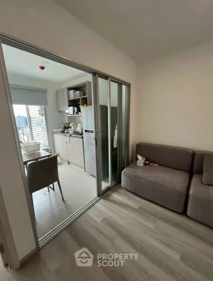 Modern apartment with sliding glass doors separating cozy living room and kitchen area.