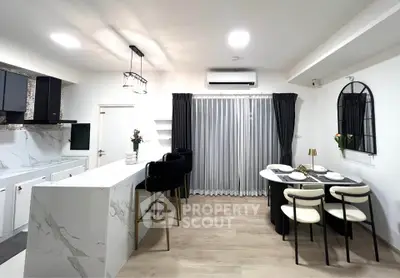 Modern kitchen with marble island and stylish dining area in open layout apartment.