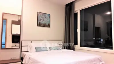 Modern bedroom with large window and stylish decor in a high-rise apartment.