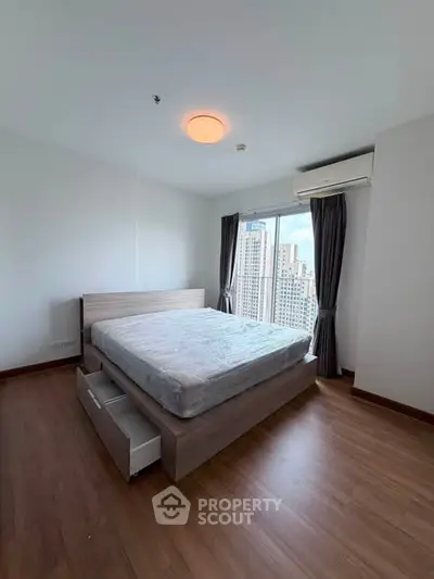 Spacious bedroom with city view, featuring modern bed and wooden flooring.