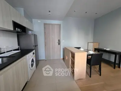 Modern kitchen with washing machine and dining area in open layout apartment.